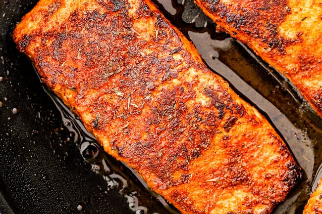  Cajun salmão em uma frigideira preta sendo cozida 