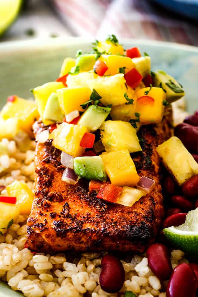  close up de pan grelhado cajun salmão em uma tigela verde com abacaxi, manga e arroz 